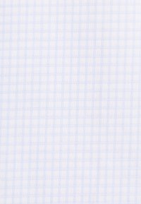 Gros plan d’un tissu blanc avec un motif à carreaux bleu clair et des détails tissés texturés.
