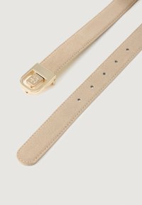 Cinturón de ante beige con hebilla rectangular en tono dorado, con logo en relieve y múltiples agujeros de ajuste sobre un fondo blanco liso.