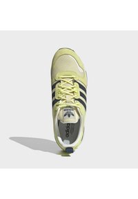 Lime green athletic shoe with mesh upper, three black stripes, round toe, and textured sole. Features branded tongue and cushioned collar.