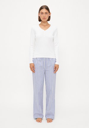 Top bianco a maniche lunghe con scollatura a V e dettagli con bottoni, abbinato a pantaloni da pigiama a quadri blu chiaro e bianchi, caratterizzati da una vestibilità ampia.