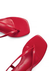 Red flat sandals with a square toe, thin straps, and a smooth leather texture. Minimalist design with a polished finish.