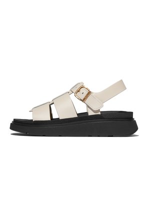 Beige leren sandalen met drie brede banden en een verstelbare enkelband. Voorzien van een dikke zwarte zool en een gouden gesp detail.