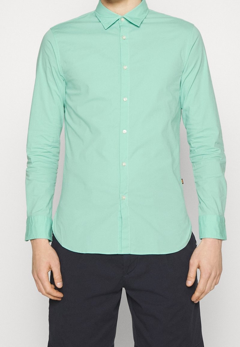 Camicia verde menta a maniche lunghe con colletto button-down, caratterizzata da un design slim fit, bottoni frontali e maniche con polsini.