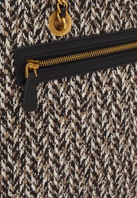 Bolso de mano tejido en negro, crema y marrón con un patrón texturizado. Presenta un cierre de cremallera de cuero negro y detalles en tono dorado.