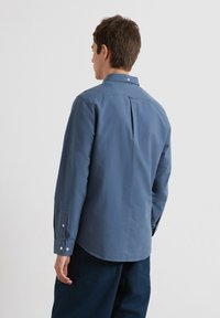 Langarmshirt van blauwe katoen met een button-down kraag, enkele knoopmanchetten en een rugplooi voor extra bewegingsvrijheid. Soepele textuur.