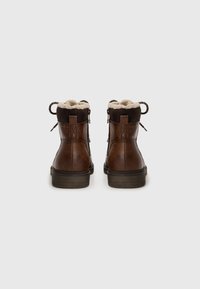 Braune Leder-Stiefeletten mit Futter aus Kunstpelz, runder Zehenpartie und tanfarbener Gummisohle. Sie verfügen über eine hintere Schlaufe und doppelte Schnürsenkel zur Anpassung.