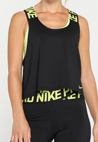 Canottiera sportiva nera caratterizzata da una vestibilità rilassata, dettagli con il logo giallo Nike sulle spalline e un design stratificato sopra una base gialla coordinata.