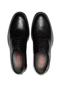 Chaussures de ville en cuir noir avec une texture lisse, design à lacets et bouts ronds ; logo rouge sur la semelle intérieure. Look minimaliste et classique.