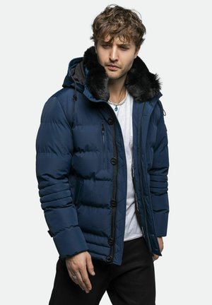 Marineblå pufferjakke med en faux fur-krave, lynlås- og knaplukning, ribbede manchetter og flere udvendige lommer. Glat, quiltet tekstur.