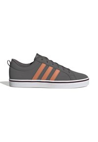 Baskets basses grises avec des rayures orange, des lacets noirs et une semelle en caoutchouc blanche bordée de brun foncé, vues de profil.