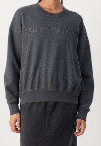 Felpa grigia con vestibilità oversize, girocollo e polsini a coste. Presenta il logo in rilievo "Marc O'Polo" sul petto. Tessuto dal morbido effetto.