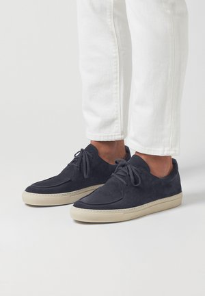 Dunkelblaue Wildledersneakers mit glatter Oberfläche, runder Zehenpartie und beigen Gummisohlen. Besitzt eine Schnürung und ein minimalistisches Design.