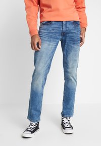 Lyseblå denimjeans med en slitt finish, rett ben-design og fem-lommers styling, sammen med svarte høye sneakers.