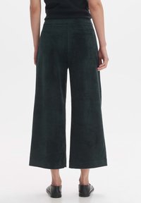 Dark green wide-leg trousers made of soft fabric, featuring a smooth waistband and a single back pocket. Flat hem with no visible patterns.
