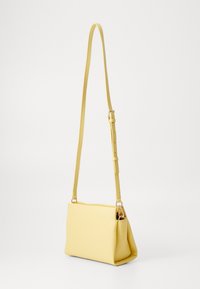 Borsa a tracolla rettangolare in pelle giallo pallido con tracolla slim regolabile e dettagli in metallo argentato su sfondo bianco.