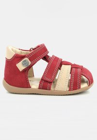 Sandalia de ante roja y beige con correas de Velcro, diseño de punta abierta y suela de goma; cuenta con costuras blancas y un detalle de logo en el costado.