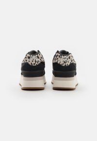 Sneaker nere e beige con un motivo a stampa leopardata sul tallone, dotate di una suola imbottita e del logo "new balance". Superfici testurizzate.