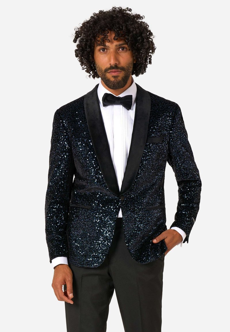 Tuxedo bunda s flitrami v námorníckej modrej farbe s čiernym saténovým klopom, so šitým strihom a jednovrstvovým zapínaním, skombinovaná s čiernymi nohavicami.