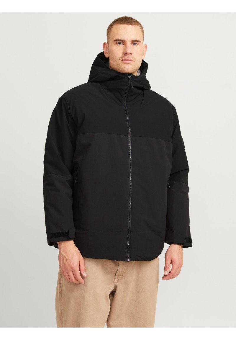 Zwarte hoodie jacket met een ritssluiting, een contrasterend paneelontwerp en verstelbare manchetten. De stof lijkt duurzaam en waterdicht.