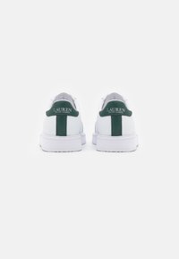 Zapatillas blancas con lengüetas verdes en el talón, de la marca "Lauren Ralph Lauren", mostradas desde atrás sobre un fondo blanco.