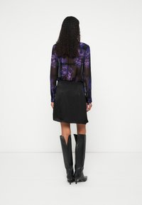 Fekete, áttetsző blúz lila virágmintákkal, fekete miniszoknyával párosítva. Térdig érő fekete bőrcsizmák V-alakú kivágással a hátulján.