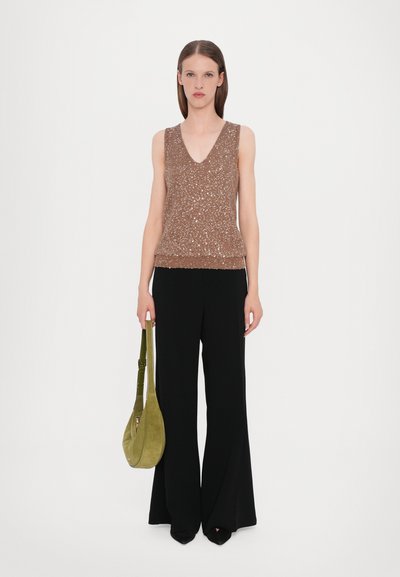 Top en tricot sans manches marron avec décolleté en V et finition texturée, associé à un pantalon noir évasé. Le modèle tient un sac à main en daim vert.