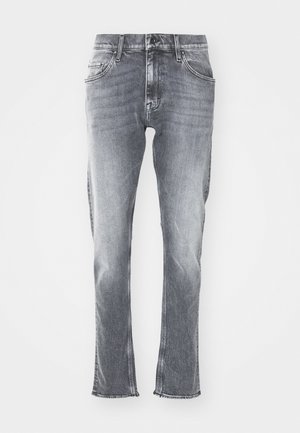Vaqueros de denim gris con un ajuste slim, dobladillo deshilachado y cinco bolsillos. Cierre clásico de botón y cremallera. Textura suave con un lavado desvanecido.