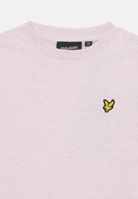 T-shirt in cotone rosa chiaro con scollatura rotonda e un piccolo logo di un uccellino nero e giallo ricamato sul lato sinistro del petto. Texture morbida.