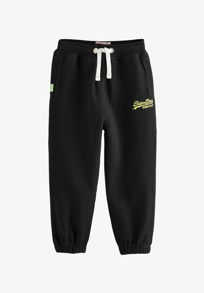 Čierne teplákové nohavice vyrobené z mäkkej tkaniny, s elastickým pásom a sťahovacou šnúrkou a elastickými manžetami. Na stehne je žlté logo.