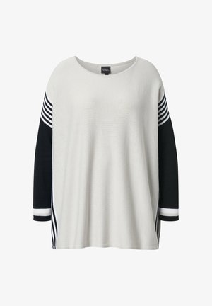 Løs, langærmet sweater med hvid front, sorte ærmer, hvide og sorte horisontale striber nær skuldre og manchetter.