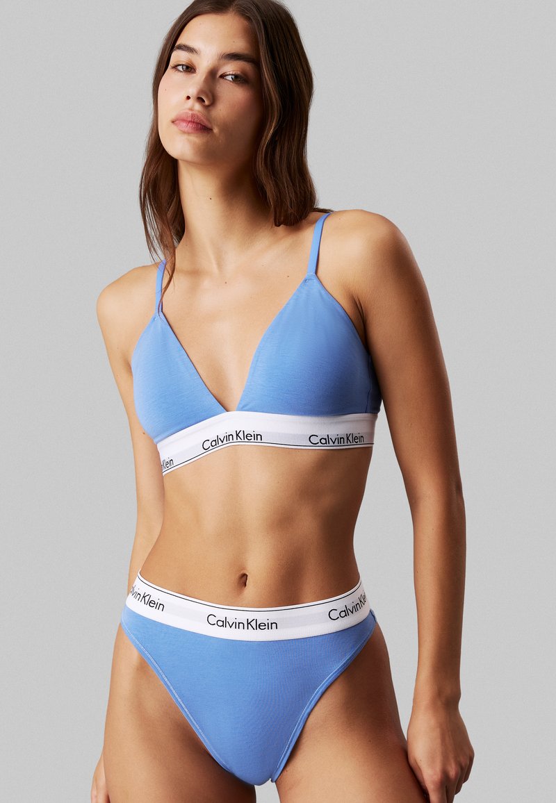 Ljusblått underklädeset med en triangulär bralette med tunna band och matchande högmidjade trosor, båda med en vit logotyp på midjebandet.