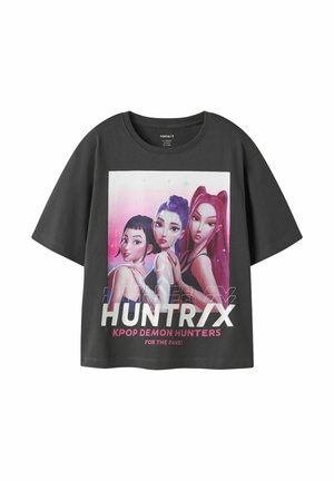 Mørkegrå T-shirt med grafik af tre stiliserede kvinder i pink og lilla nuancer, tekst "HUNTRIX KPOP DEMON HUNTERS FOR THE FANS!" foran.