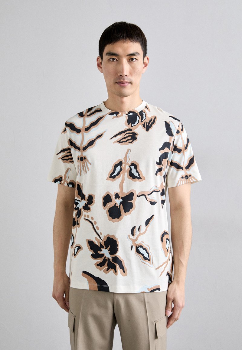 Kortærmet mønstret t-shirt i creme med abstrakte blomsterdesigns i sort, brun og blå. Blødt stof, afslappet pasform, rund halsudskæring.