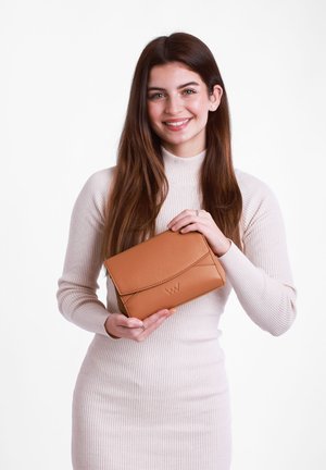 Braune Lederclutch mit einem Klappenverschluss, ausgestattet mit geprägtem Logo und minimalistischen Nähdetails. Modell hält die Tasche vor einem weißen Hintergrund.