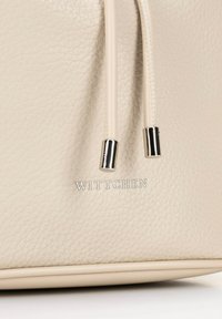 Sac à main en cuir beige avec surface texturée, doté de deux cordons clairs et de caps métalliques. Logo "WITTCHEN" embossé sur le devant.