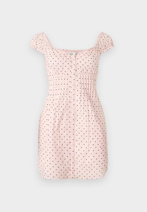 Robe courte rose clair à pois noirs, encolure carrée, manches courtes froncées, boutonnage sur le devant et plis cintrés à la taille.