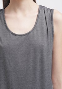 Szary bezrękawnik z okrągłym dekoltem, wykonany z miękkiego materiału z delikatnym wzorem teksturowym i lekko drapującym efektem.