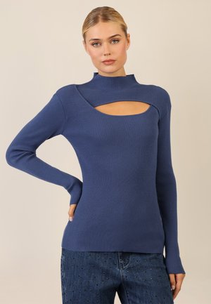 Rippstrickpullover mit langen Ärmeln in Dunkelblau, mit Stehkragen und Ausschnittdetails an der Brust, kombiniert mit Denim mit dezenten Verzierungen.