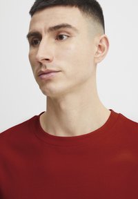 Red cotton t-shirt with a round neckline and short sleeves, featuring a smooth texture and minimalistic design.