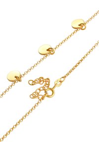 Collier en chaîne dorée comprenant des disques ronds et plats ainsi qu'un fermoir circulaire. La chaîne a une texture délicate avec des maillons espacés uniformément.