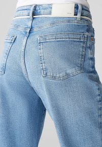  Lichtblauwe denim jeans met een hoge taille, voorzien van twee achterzakken en een wit merketiket op de tailleband. Glad oppervlak, rechte pasvorm.