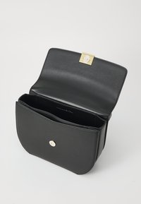 Svart läder crossbody-väska med en böjd form, guldfärgad låsning och ett enda fack. Smidig textur, minimalistisk design.