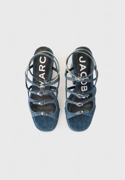Denimsandaler med flera korsettskaft, fyrkantig tå och texturerat material. Svart innersula med vitt "JACOB"-logotyp. Silverfärgade detaljer.