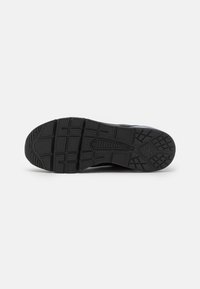 Black athletic shoe sole with a textured pattern, featuring deep lugs for traction and a curved design at the toe for flexibility.