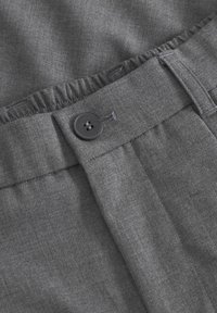 Hallhalli riie, millel on sile tekstuur, nupulukuga ja volangiga vöökoht. Lõige on kohaliku disainiga, rõhutades struktureeritud voldikuid.