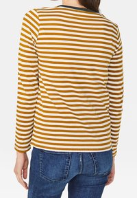 Långärmad tröja med växlande senapsgula och vita ränder, tillverkad av mjukt tyg med rundad hals och en figurnära silhuett.