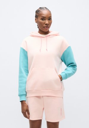 Pastelroosa ja türkiissinise tooniga kapuutsiga dressipluus, millel on esiosas tasku, soonilised varrukasuuäärised ning veidi lõdvem lõige. Sobitatud sobivate lühikestega.