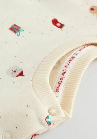 Lichte crèmekleurige romper met feestelijke versieringen, waaronder sneeuwpoppen, cadeautjes en wanten. Ribbelkraag en een stervormige drukknoop.