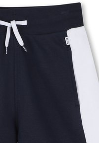 Pantalons de survêtement bleu marine avec un panneau latéral blanc. Fabriqués en tissu doux, dotés d'une taille avec cordon de serrage et d'une petite étiquette de marque.