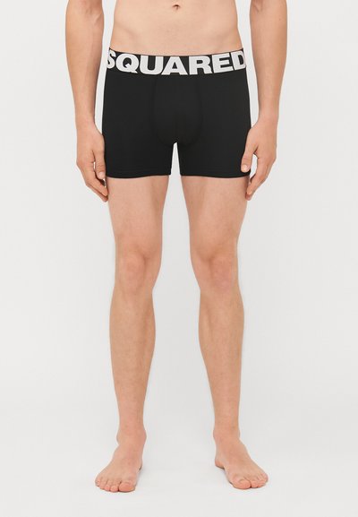 Sorte boxer shorts lavet af strækbart stof med en bred hvid talje, hvor der står "SQUARED" trykt i stort.